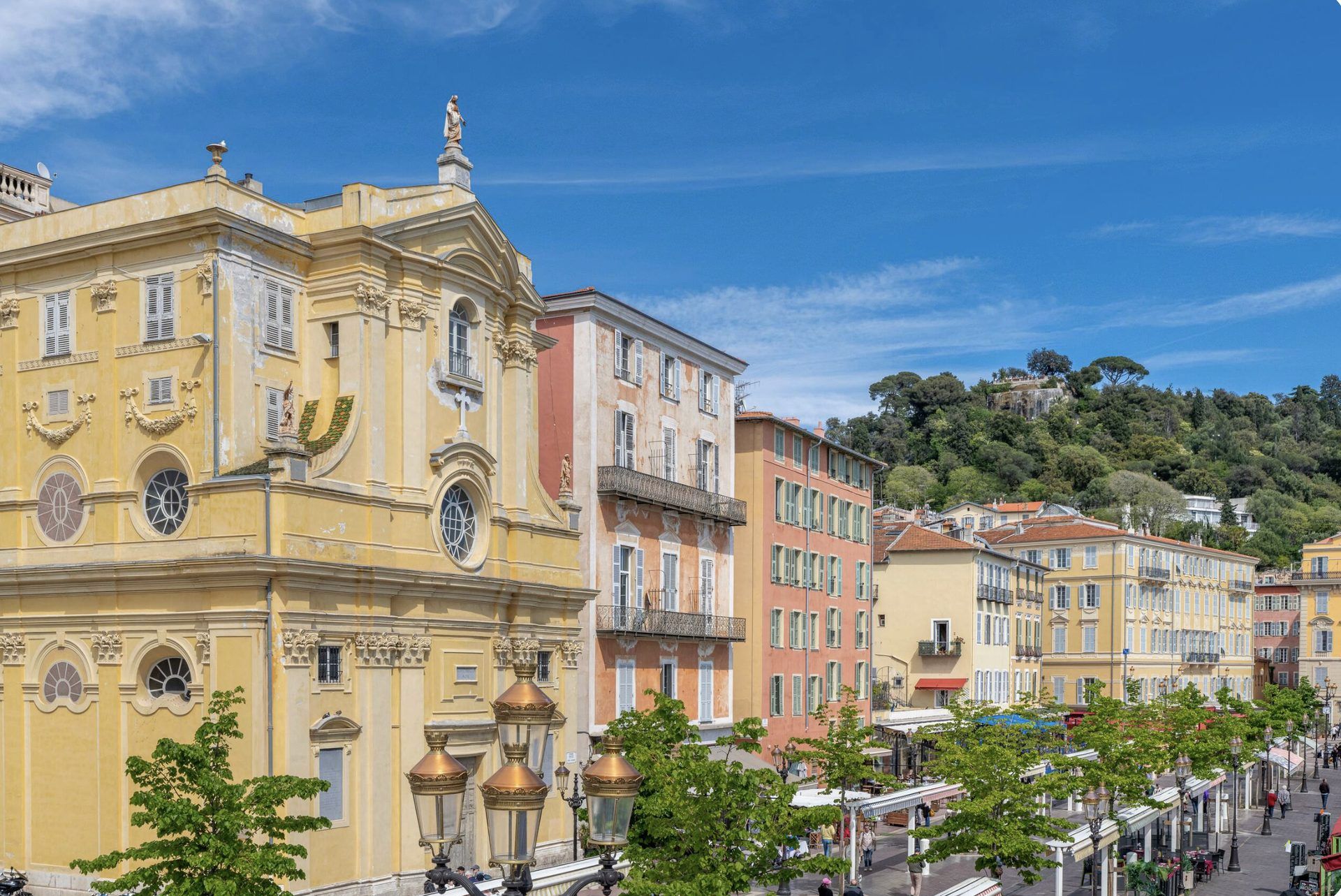 View from Gilli over the Cours Saleya — the ochre Chapelle de la Miséricorde, colourful Old Town facades, and Castle Hill behind